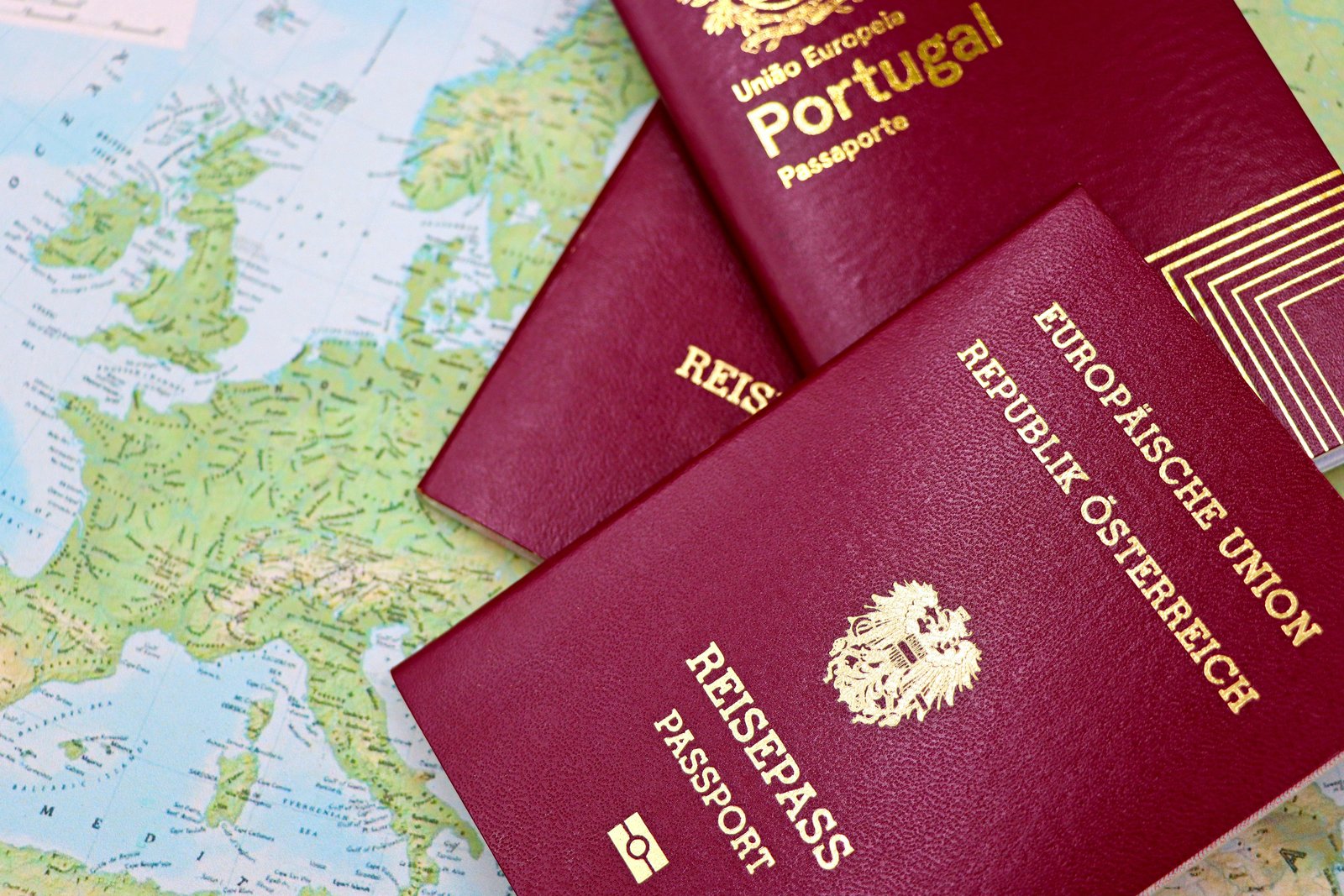 Mehrere europäische Reisepässe auf einer Landkarte als Symbol für Auswandern, Reisen und internationale Unfallversicherung ohne Wohnsitz